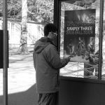 A person points a phone at a poster affixed to a bus stop.