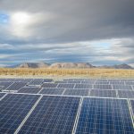 A field of solar panels with mountains in the background