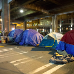 A view of people suffering from homelessness and living on in tents on a Seattle street.