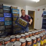Tukwila Pantry Executive Director Joe Tice stocks the tables with canned goods. The pantry provides monthly food bank services to individuals and families in cities of Tukwila, SeaTac, Burien, and the Boulevard Park community.