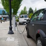 A black electric vehicle plugged into a charging station in Hillsboro, Oregon.