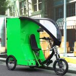 Bright green cargo bike parked outside of a shop.