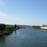 A view of the Duwamish River from South Park Bridge Seattle. The river is lined with houses and trees on the left, and commercial buildings on the right.