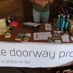 A table with a large poster that says "the doorway project: a place to be".
