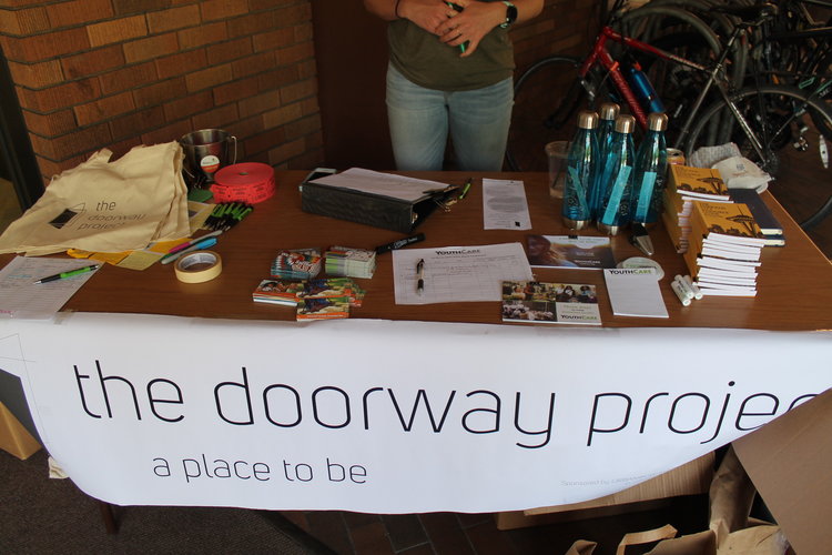 A table with a large poster that says "the doorway project: a place to be".