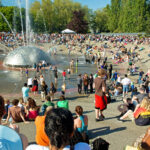 A large, multigenerational group of people by the International Fountain at Seattle Center on a sunny day