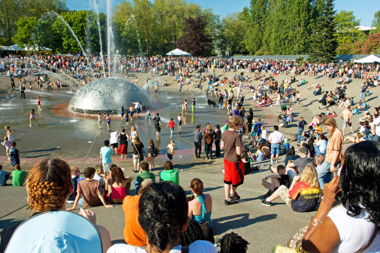 A large, multigenerational group of people by the International Fountain at Seattle Center on a sunny day