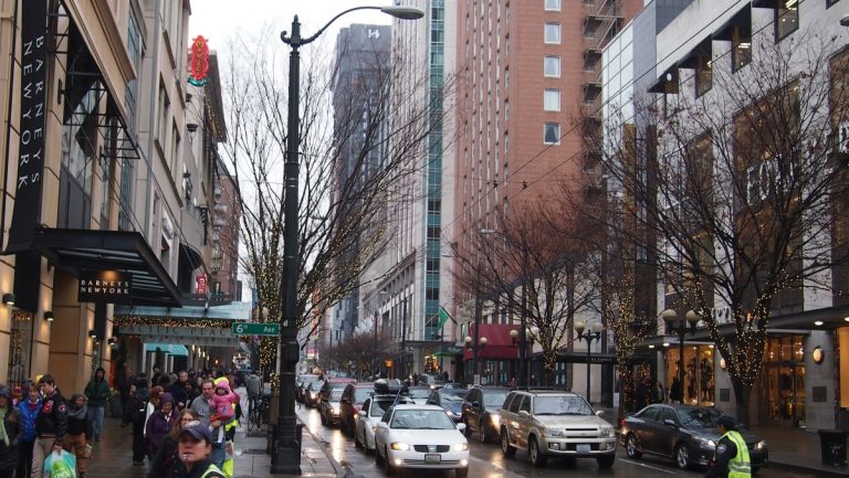 Pedestrians and vehicles at busy intersection amid mixed use development in downtown Seattle.