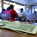 Dollar bills and quarters on a table in a restaurant