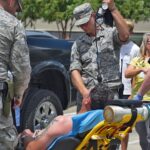 Flood evacuee in stretcher outdoors being treated for heat stroke with IV by two National Guard members in Baton Rouge, Louisiana.