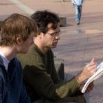 one man showing another a drawing on campus